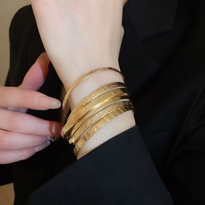 Detail of 6-piece gold bangle set with LOVE engraving and textured geometric patterns
