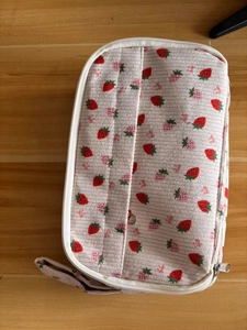 Detail view of strawberry corduroy pouch with multiple compartments and zipper
