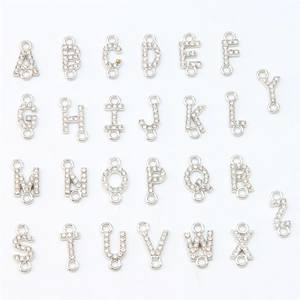 Macro detail of silver alloy A-Z alphabet charms with diamonds and double rings