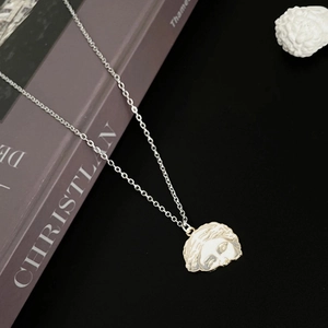 Close-up of silver Venus relief pendant on stainless steel chain with artistic props