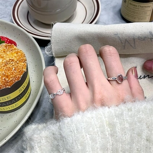 Detailed view of 925 sterling silver chain ring and pink oval gemstone ring on model's hand