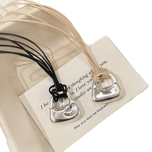 Collana minimalista con ciondolo a borsa argentata e cordini neri e color beige