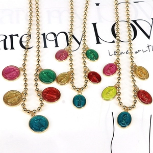 Close-up of golden ball chain necklaces with colorful enamel religious pendants