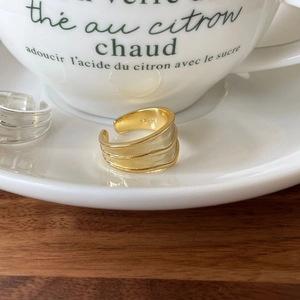 Detail shot of a three-layer wavy S925 silver ring featuring a polished gold finish
