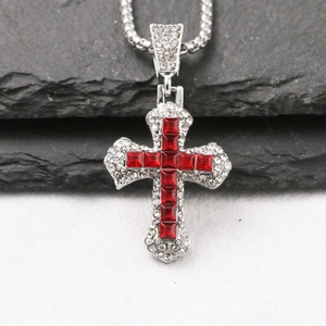 Detailed close-up of a silver cross necklace with red zircon stones and small white crystals