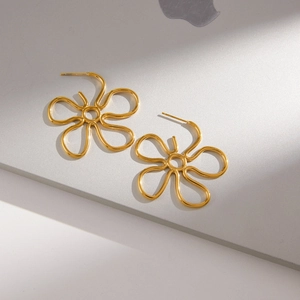 Detailed view of hollow flower stud earrings in polished gold-plated stainless steel finish