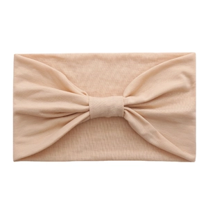Elastic cotton yoga headband in apricot color featuring a central bow decorative design