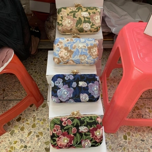 Stack of embroidered evening clutch bags with floral pearl detailing in various colors