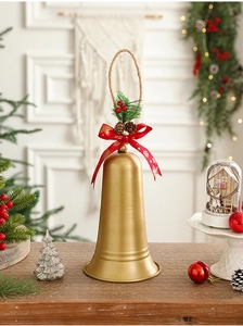 Golden Christmas bell with red bow and pine needle accents on a rustic hanging rope