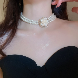 Macro shot of multi-layer pearl choker necklace featuring a sparkling diamond flower pendant