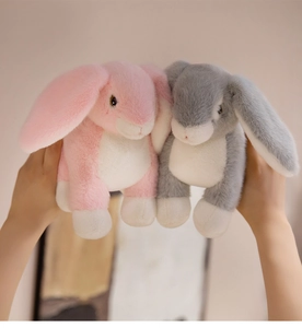 Close-up of soft plush bunny toys in pink and gray with long floppy ears and furry texture