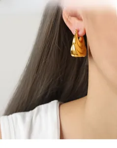 Close-up of polished gold-plated teardrop earrings with a thick, irregular geometric design