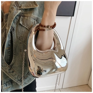 Close-up of a silver mirror acrylic handbag with sculptural curves and chain strap