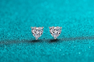 Macro shot of S925 sterling silver heart-cut moissanite earrings on blue background