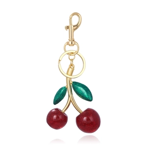 Close-up of sparkling red glitter cherry keychain with green leaves and gold clasp
