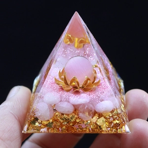Pink crystal resin pyramid with golden lotus base and gold foil, held in hand