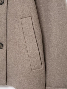 Macro detail of taupe wool coat showing welt pocket and premium resin buttons texture
