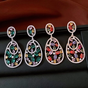 Close-up of vintage oval zircon drop earrings in silver and rose gold on black leather