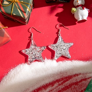 Close-up of sparkling star-shaped resin earrings with silver glitter on festive red background
