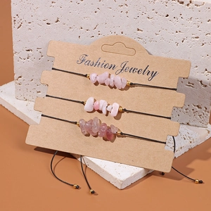 Detailed view of three natural pink crystal stone bracelets on a brown jewelry card