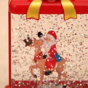Macro detail of Christmas water globe featuring Santa on reindeer with floating glitter