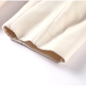 Close-up of the textured off-white wool fabric on the sleeve cuff of a V-neck jacket