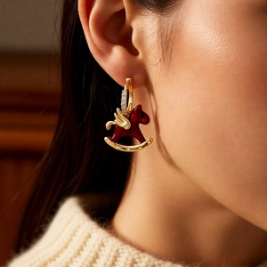 Close-up of model wearing a gold Pegasus earring with red enamel and zircon stones