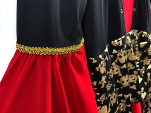 Detail of red and black pirate costume fabric with gold lace and skull print