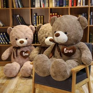 Close-up of plush teddy bear with Love embroidery and silk bow on a cozy wooden shelf