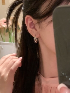 Close-up of a silver metal hoop earring shown on ear for minimalist style