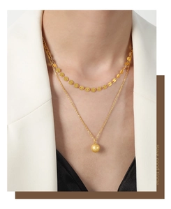 Detail of double-layer gold necklace featuring a matte bead pendant and polished discs