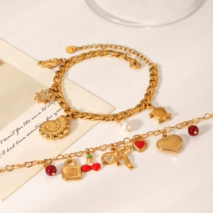 Detail of gold-plated stainless steel charm bracelets with sea motifs and heart pendants