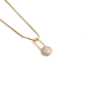 Detailed view of gold safety pin pendant with micro-paved zircons on a box chain