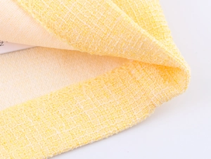 Dettaglio del tessuto tweed giallo che mostra la trama intrecciata e la finitura del bordo