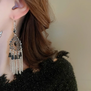 Detail of silver drop earrings with black gemstone and long tiered metal tassels