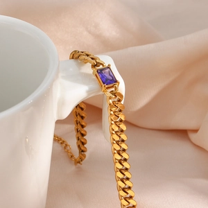 Dettaglio del bracciale cubano dorato con zircone viola su una tazzina da caffè