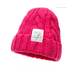 Close-up of rose red knitted beanie featuring a white rectangle label with text details