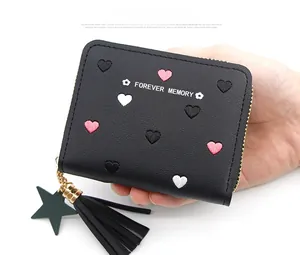 Detailed view of a compact black zip wallet featuring heart embroidery and star charm