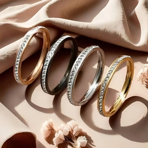 Macro view of four elegant stainless steel rings with single row sparkling stones on fabric