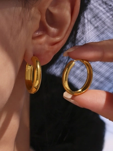 Close-up of chunky gold hoop earring showing high-polished finish and 18K gold texture