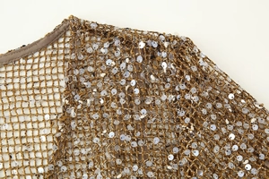 Détail du tissu en maille à paillettes montrant des sequins sur une robe dorée