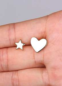 Detailed view of asymmetric gold-plated star and heart stud earrings held by hand