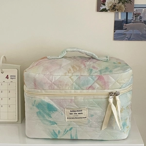 Close-up of quilted watercolor wash makeup bag with ribbon zipper and woven label