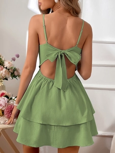 Detail of green summer dress featuring an open back with a large bow and tiered skirt