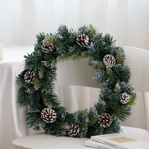 Nordischer Weihnachtskranz mit Zapfen und Schneeeffekt auf einem weißen Stuhl