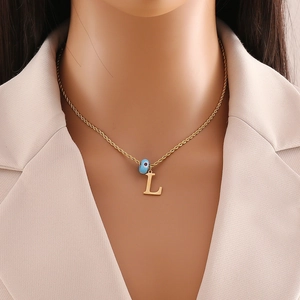 Detailed view of gold twisted chain with letter L pendant and blue evil eye charm