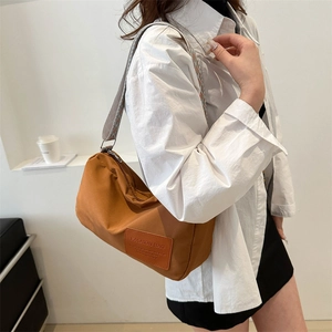 Brown nylon crossbody bag with wide patterned strap and fashionable leather patch label