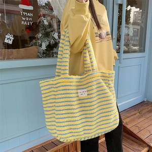Model showing a large yellow and blue striped plush tote bag in a winter outdoor setting