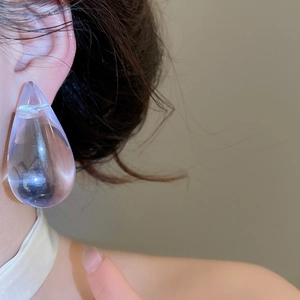 Close-up of a transparent lavender acrylic water drop earring worn by a model