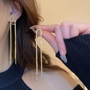 Détail de boucles d'oreilles longues à pampilles dorées avec design à nœud
